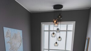 A stairwell with a modern design, a large window with blinds, a hanging light fixture, and a framed map on the wall.