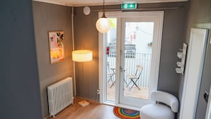 A modern room with a radiator, a lamp, a chair, and a door leading to an outdoor area with a balcony.