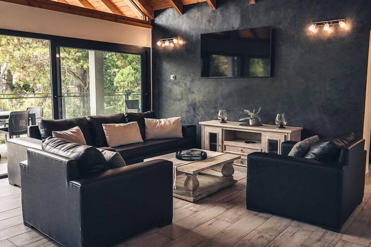Una sala de estar moderna con una pared oscura, un televisor de pantalla plana y una mesa de centro de madera.