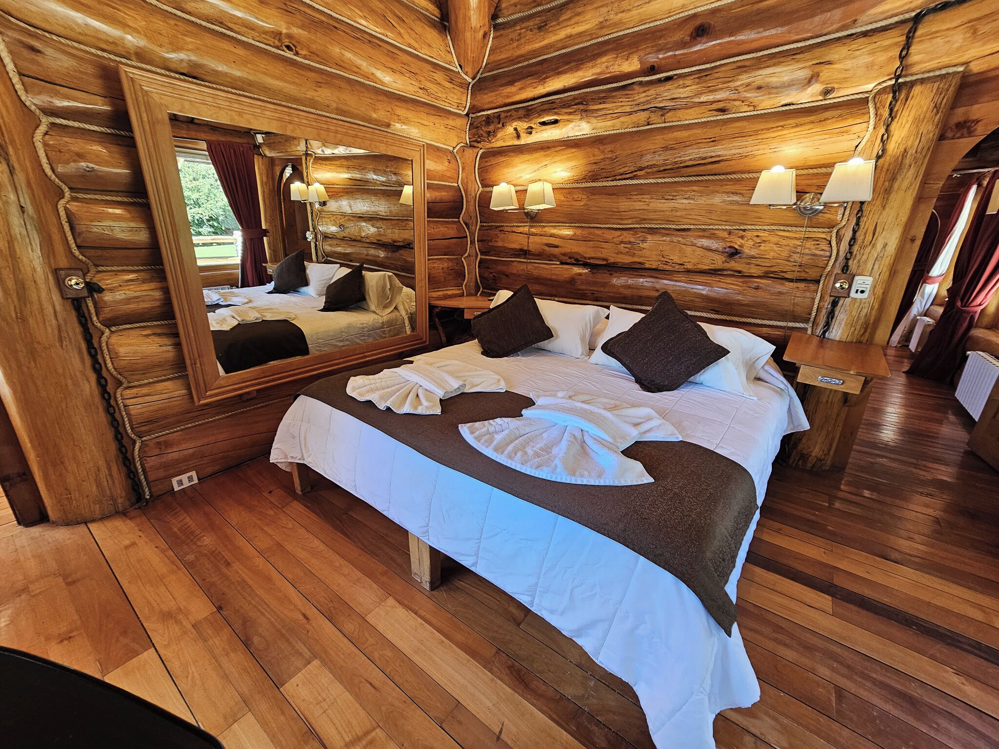 Ein schlicht eingerichtetes Schlafzimmer im Chalet-Stil mit einem großen Bett, einem Spiegel und zwei Wandleuchten.