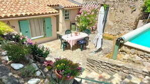 A patio area with a table and chairs, surrounded by potted plants and a stone wall.