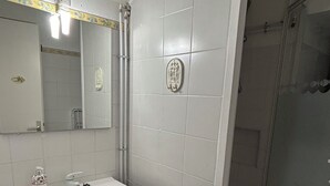 Une salle de bain avec un lavabo blanc, un meuble-lavabo foncé et une cabine de douche en verre.