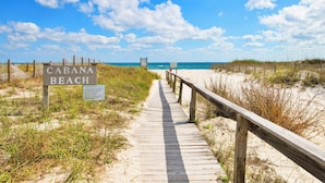 Une promenade en bois mène à une plage où un panneau indique : « CABANA BEACH ».