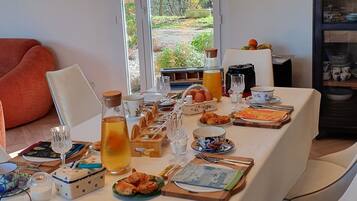 A dining table set with various food items and drinks, surrounded by modern chairs and pendant lights.