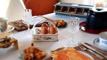 Een ontbijttafel gedekt met croissants, eieren en een koffiezetapparaat.