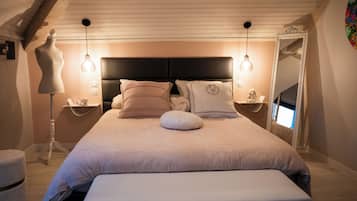 A bedroom with a large bed, two bedside tables, a dresser, a mirror, and a mannequin.