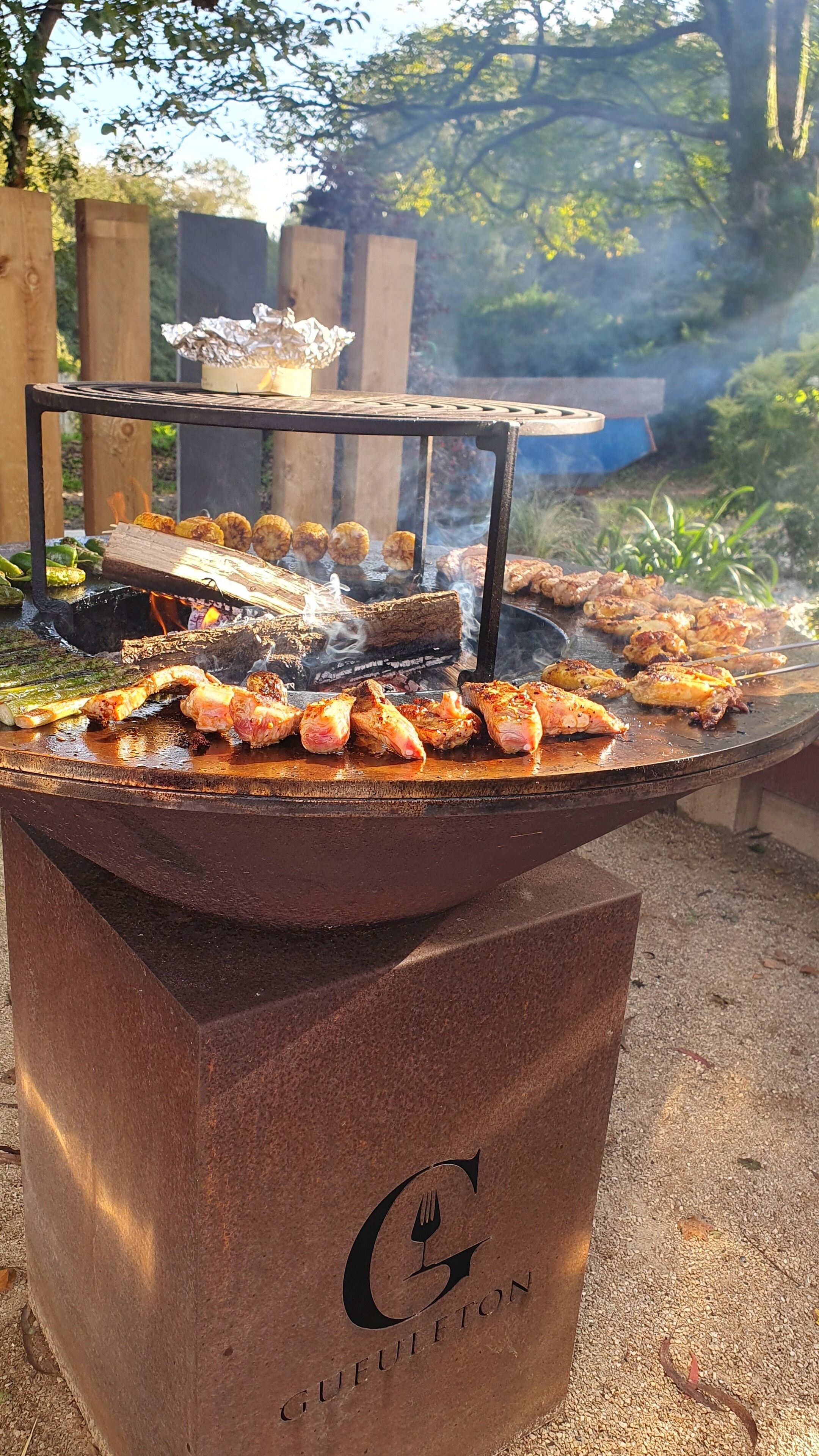 Una parrilla con diversos tipos de carne y verduras asándose al aire libre.