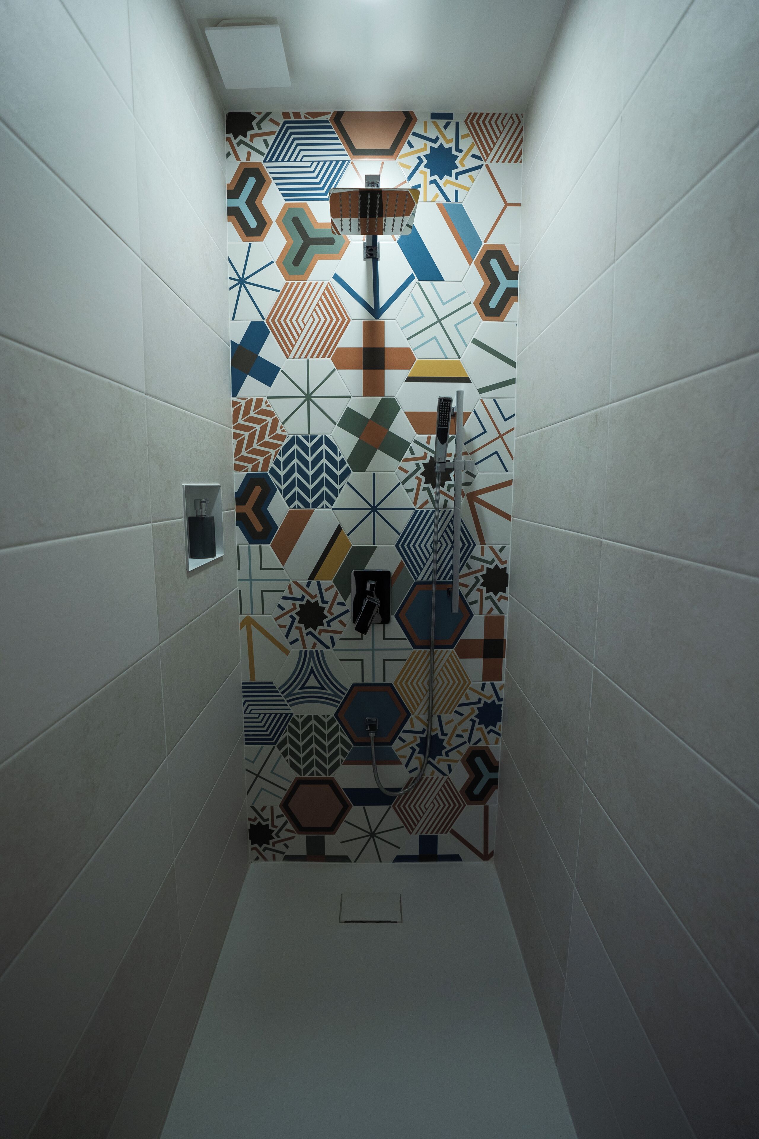 A narrow hallway with patterned tiles on the walls and a shower stall with a geometric tile design.