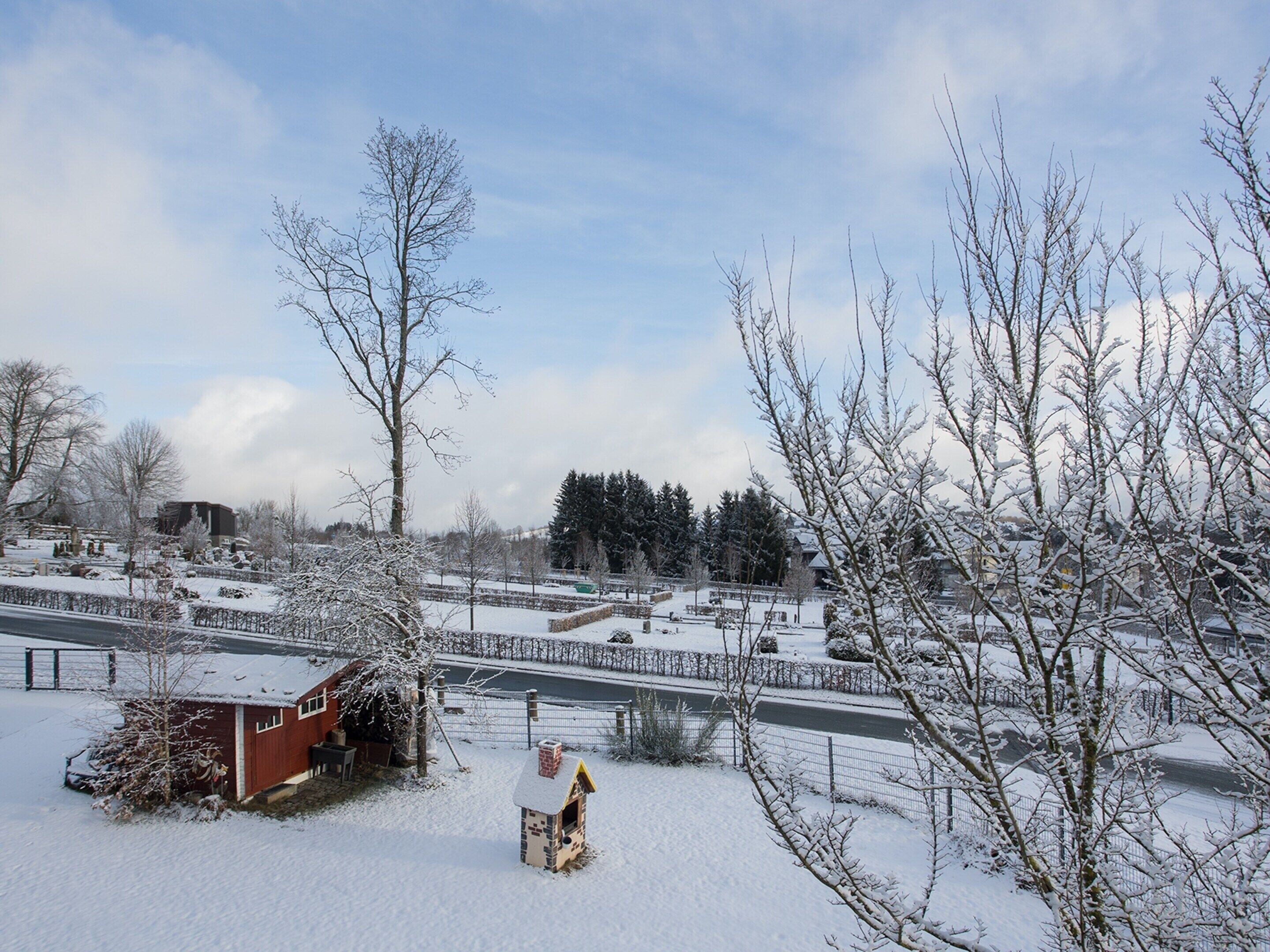 A snow-covered landscape with a small wooden structure and a fenced area.