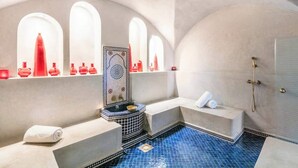 Une salle de bain avec un sol carrelé de carreaux bleus, un lavabo blanc, un miroir avec un cadre décoratif et un espace douche.