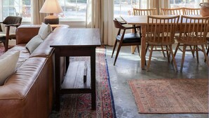 A spacious room with a large window, a wooden dining table, a sofa, and a rug. - This Maine House-Near Ocean! (Tremont)
