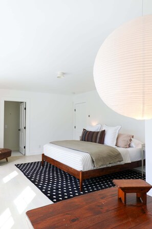 A bedroom with a bed, bedside table, and a hanging light fixture.