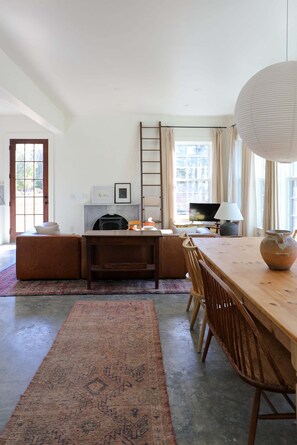 Un grand salon doté d’une cheminée, d’un téléviseur et d’une table à manger avec des chaises.