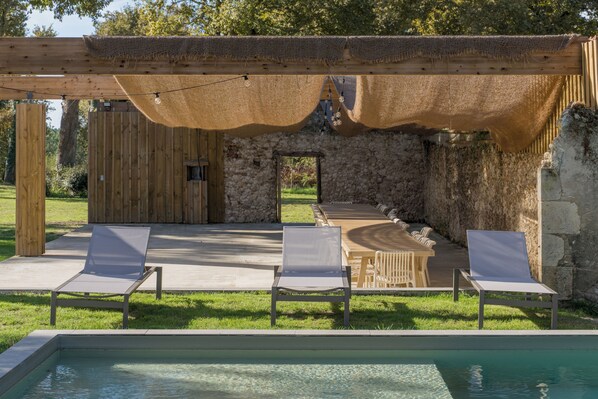 An outdoor pool area with lounge chairs and a pergola.