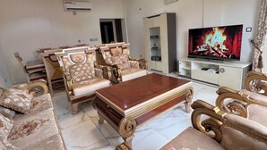 A luxurious living room with ornate furniture, a television, and a fireplace. - Lorena House, furnished apartment (Yaoundé)