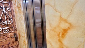 A marble wall with a metallic elevator and a wooden door with intricate metalwork. - Lorena House, furnished apartment (Yaoundé)