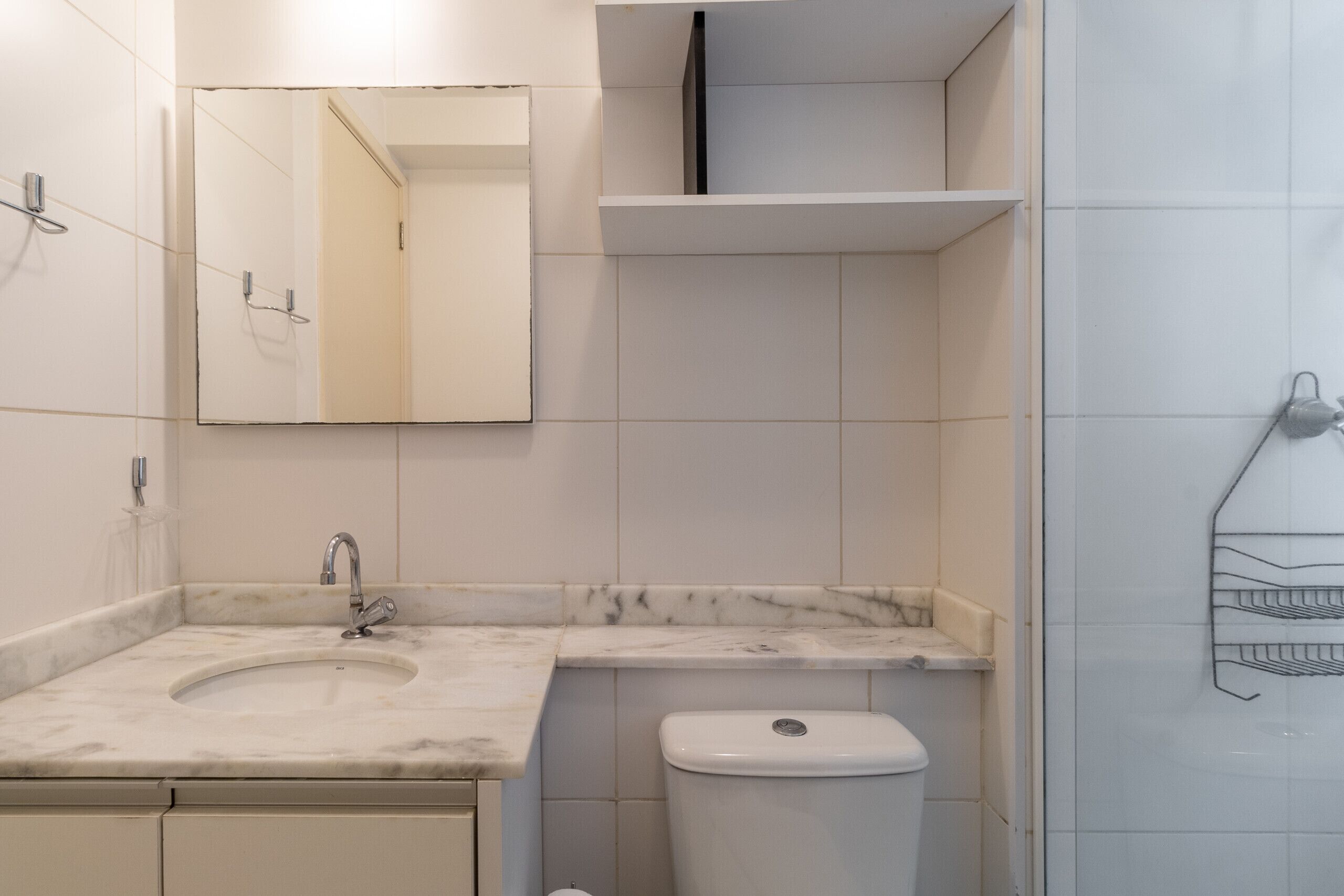 A bathroom with a sink, mirror, toilet, and shower area.