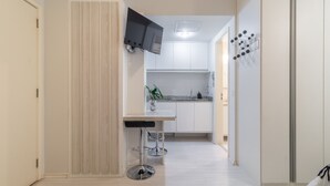 Een moderne keuken met witte kastjes, een ingebouwde televisie en een bar met krukken.