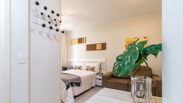Een moderne hotelkamer met een bed, nachtkastje en een grote plant.