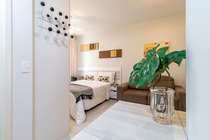 Een moderne hotelkamer met een bed, nachtkastje en een grote plant.