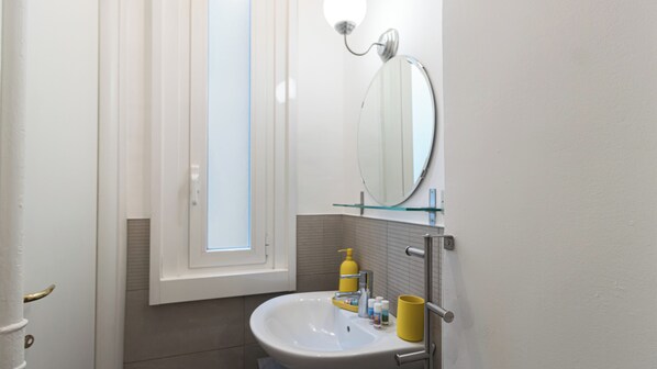 A bathroom with a white sink, a mirror, and a window with blinds. - Italianway Easy - Lepetit 4 (Milan)