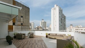 Une terrasse sur le toit, aménagée avec du mobilier d’extérieur, des plantes en pot et offrant une vue sur le panorama urbain.