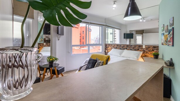 Un salon moderne avec une grande fenêtre, un canapé, une table basse et une plante en pot.