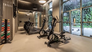 Une salle de sport équipée de vélos d’exercice, de tapis de course et d’un banc de musculation.