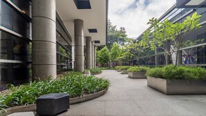 Un bâtiment moderne doté de larges piliers en béton, d’une allée centrale et de jardinières agrémentées de verdure.