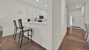 Una cocina moderna con armarios blancos, un microondas y un reloj en la pared.