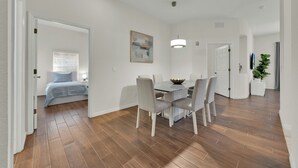 Un comedor moderno con suelo de madera, paredes blancas y una mesa con sillas.