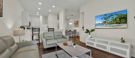 A modern living room with a sofa, coffee table, and a TV mounted on the wall.