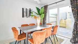 A dining area with a table and chairs, a ceiling fan, a large plant, and a view of the outdoors through a sliding door. - Host & Stay | Hazelnut House (Launceston)