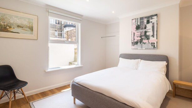 A bedroom with a bed, a chair, a window, and artwork on the walls. - Host & Stay | Prince Albert (Margate)