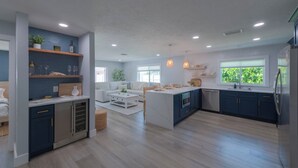 Une cuisine moderne dotée d’un îlot central, de meubles de rangement intégrés et d’un coin repas avec un canapé blanc.