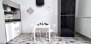 A compact kitchen with a built-in stove, a sink, and a dining area with two white chairs and a small table. - Blu Bed (San Giovanni Teatino)