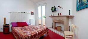 A bedroom with a bed, a chair, a fireplace, a television, and a window. - Blu Bed (San Giovanni Teatino)