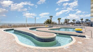 Un área de piscina con varias piscinas y sillones de descanso.