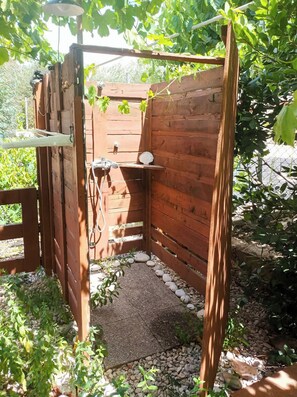 A wooden outdoor shower area with a stone pathway, surrounded by greenery. - Marina's Cozy Escape-Sea & Sun Getaway (Romanos)