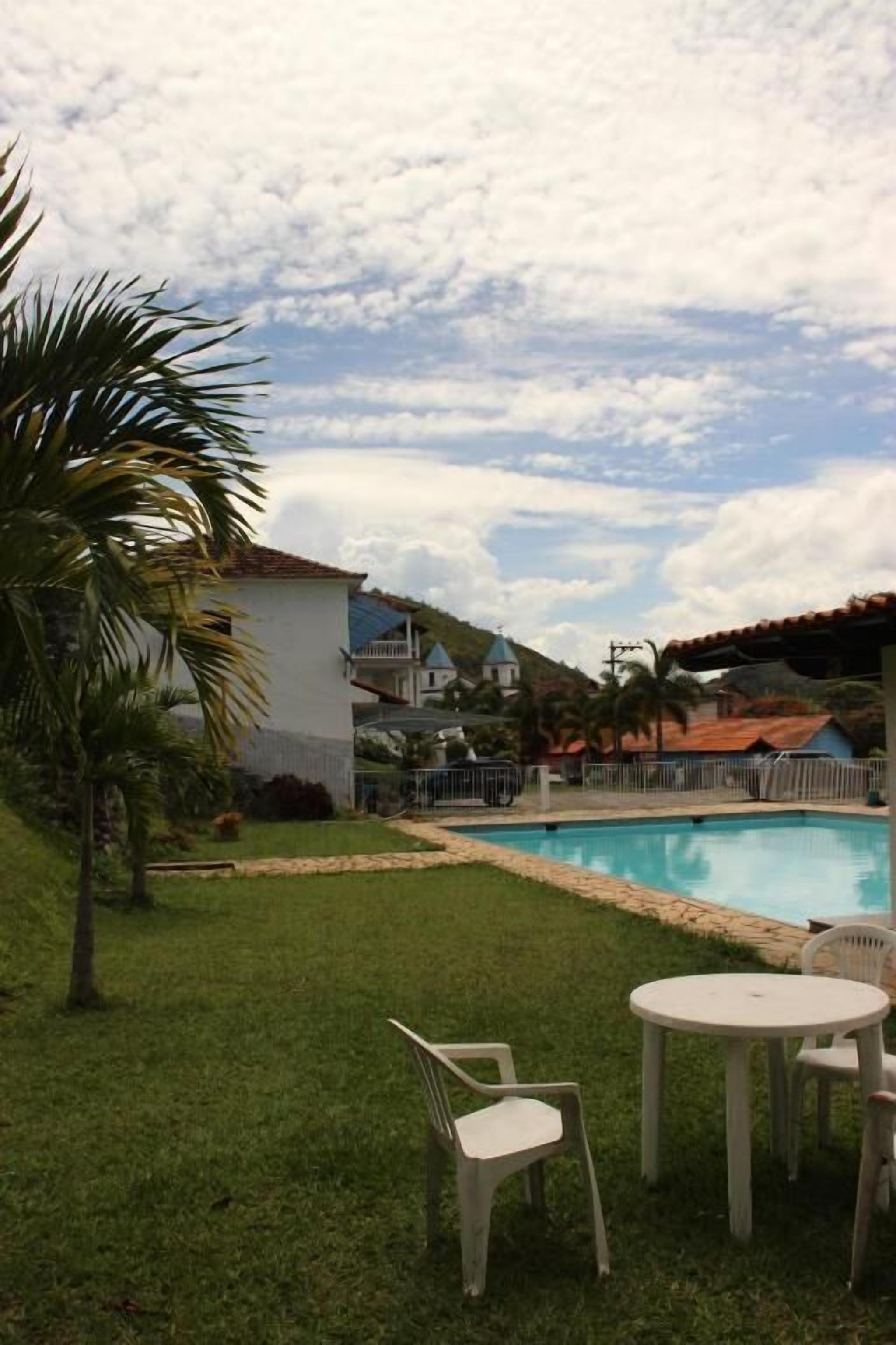 Una piscina amb una zona enjardinada, una taula petita i cadires.