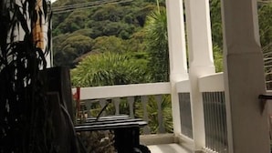 Un balcón techado con vistas a una ladera verde exuberante.