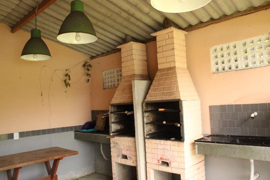 A kitchen with two brick ovens, a wooden table, and hanging lights.