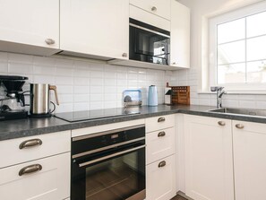 A modern kitchen with white cabinets, a built-in oven, a microwave, and a coffee maker. - 4 Star Holiday Home in Laeso (Læsø)
