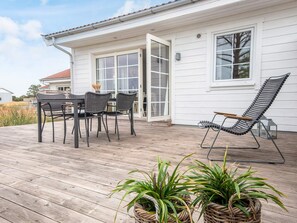 A deck with a table and chairs, a lounge chair, and potted plants. - 4 Star Holiday Home in Laeso (Læsø)