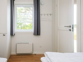Una habitación con ventana, radiador, puerta y cama.