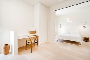 A minimalist bedroom with a bed, a desk, and a chair. - Luxury Trullo with Infinity Pool & Design (Ostuni)