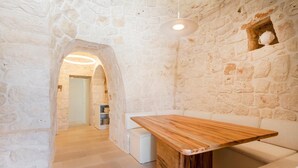 Une pièce aux murs de pierre, avec une table en bois et un canapé blanc.