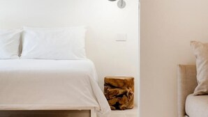 Une chambre à coucher au style minimaliste, avec un lit, une lampe de chevet et un tabouret en bois.
