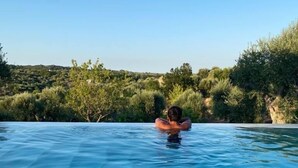 Une piscine d’eau cristalline où l’on voit une personne sur un flotteur gonflable rouge.