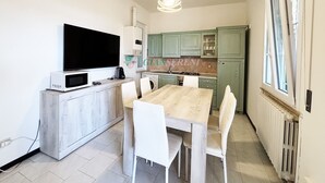 A modern kitchen with a dining area, a flat-screen TV, and a built-in oven.